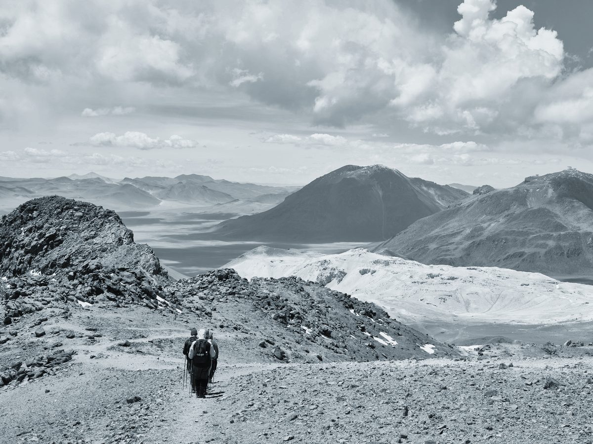 A lone hiker walking a rocky mountain trail